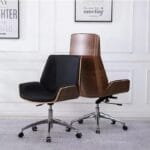 Jurish High Back Executive Chair featuring a walnut veneer shell, black PU upholstery, aluminium base with nylon castors, and single-locking knee tilt mechanism, set in a modern office environment.